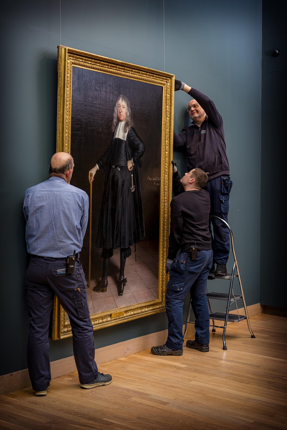 Van Hoogstraten toegevoegd aan collectie Dordrechts Museum. Het schilderij wordt opgehangen op zaal door twee medewerkers.