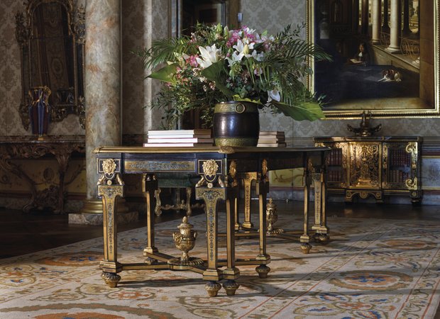 In een luxueus appartement hang de Van Hoogstraten aan de muur. Er staat een tafel met boeken op de voorgrond.