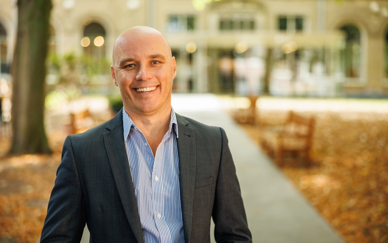 Zakelijk directeur André Besseling staat lachend in de museumtuin. Het is herfst.