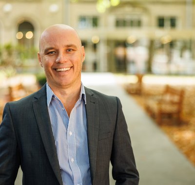 Zakelijk directeur André Besseling staat lachend in de museumtuin. Het is herfst.