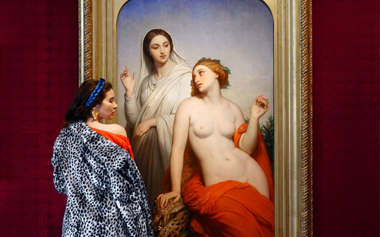 Vrouw met ontblote schouder staat naast het schilderij Hemelse en Aardse liefde, met een geklede en een naakte vrouw.