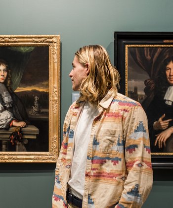 Jongen kijkt naar een schilderij van een jonge man in sjieke kleding.