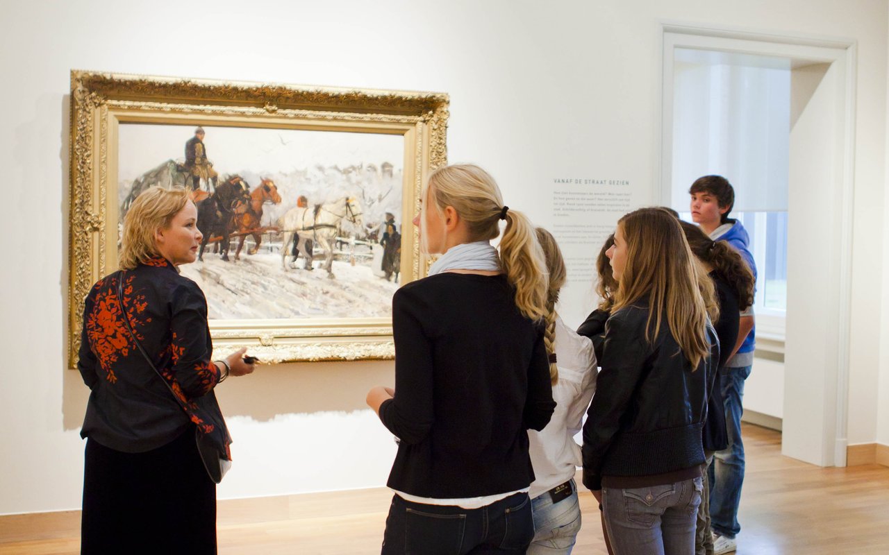 Een groep scholieren staat stil voor een schilderij in het Dordrechts Museum en krijgt uitleg, tijdens het Schoolprogramma Waardevol of Waardeloos.