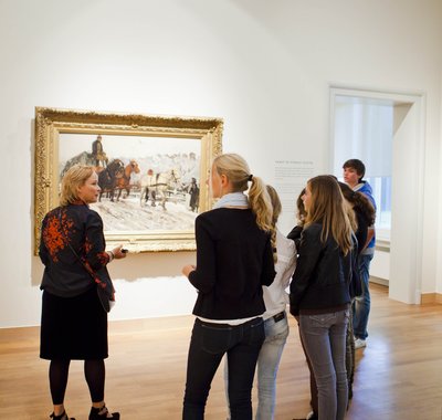 Een groep scholieren staat stil voor een schilderij in het Dordrechts Museum en krijgt uitleg, tijdens het Schoolprogramma Waardevol of Waardeloos.