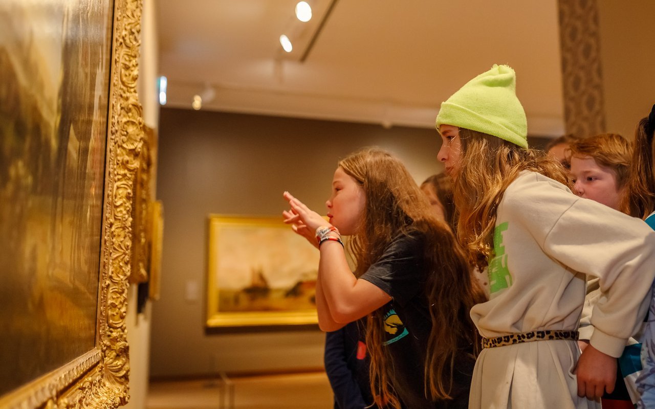 Twee jonge meisjes met daarachter nog meer leerlingen, kijken naar een schilderij in Dordrechts Museum tijdens Schoolprogramma Kijken is een kunst.