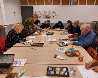 Workshop 'Cuyp op de koffie' waarbij mensen aan tafel tekenen. Op locatie van Buurtwerk Dordrecht bij Trefpunt de Nieuwe Stoof in Crabbehof.