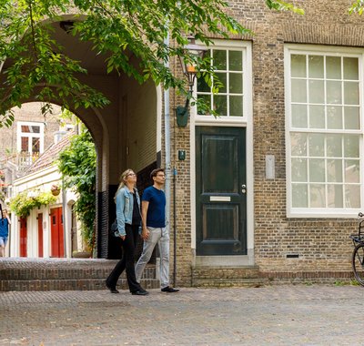 Een man en vrouw lopen hand in hand het Hofplein op. Ze kijken rond. Er staan fietsen geparkeerd.