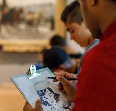 Jongeren maken tekeningen terwijl ze in het museum zijn.