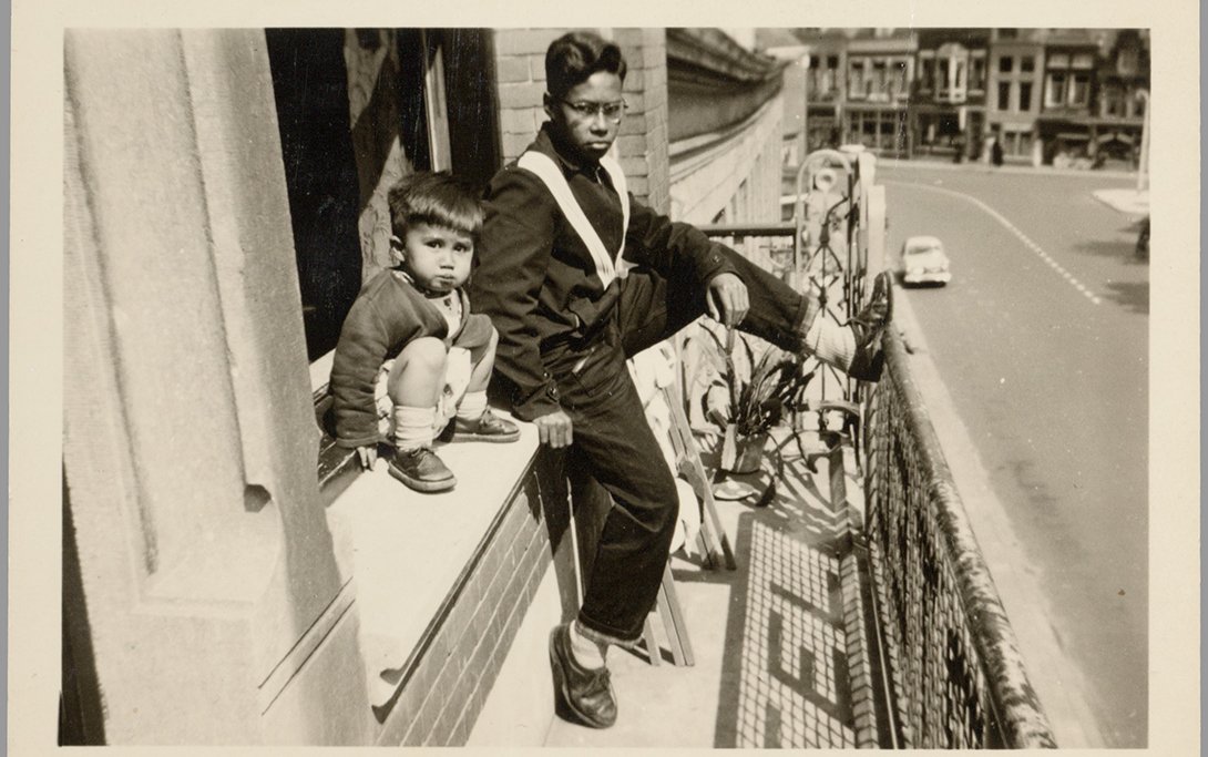 Emmy Verhoeff - Twee Indische kinderen zitten in het raam van contractpension het Oranjehotel in Dordrecht - ca. 1955-1956