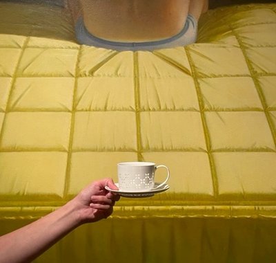 Voor het kunstwerk BED van Jan Beutener, houdt iemand een koffiekopje omhoog.