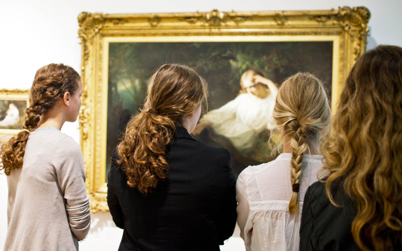 Vier meisjes met lange haren staan voor het werk mijmering met daarom een jonge vrouw.