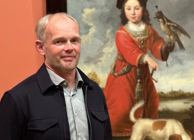 Man staat voor een schilderij van een jongetje in rode jas met valk op zijn arm.